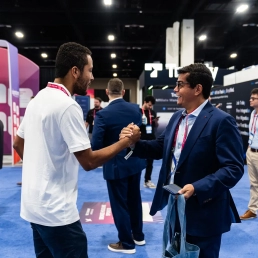 Two attendees shaking hands on the exhibition floor at SBC Summit Americas gaming industry conference