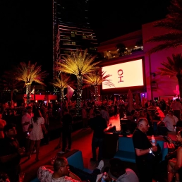 Red lit crowd and palm trees at the SBC Summit Americas Infinity closing party at Daer Dayclub